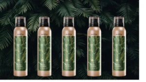 Five bottles of Aveda Texture Tonic hair finishing spray arranged in front of green leafy foliage
